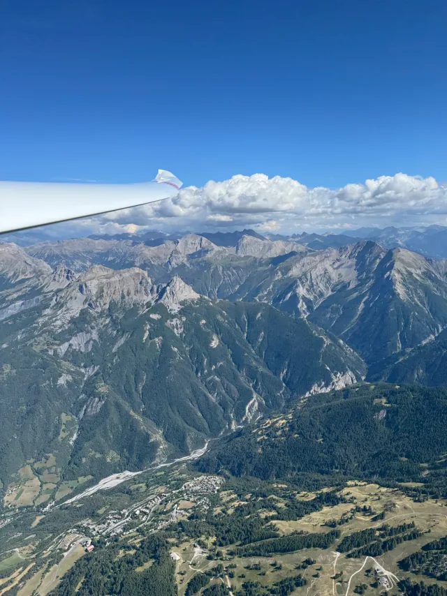 A glider wing above a mountain ridge